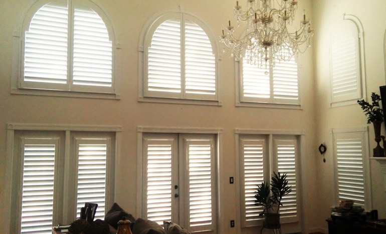 Great room in open concept Dallas home with plantation shutters on high ceiling windows.