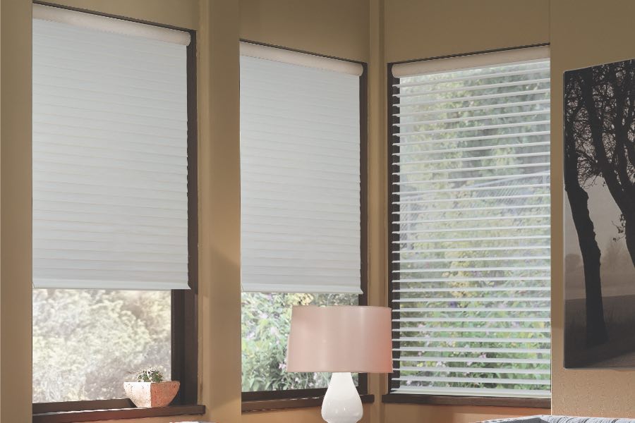 Opaque motorized window shades in Dallas keep hot UV rays out of your home. Gray motorized sheer shades on corner windows next to gray furniture
