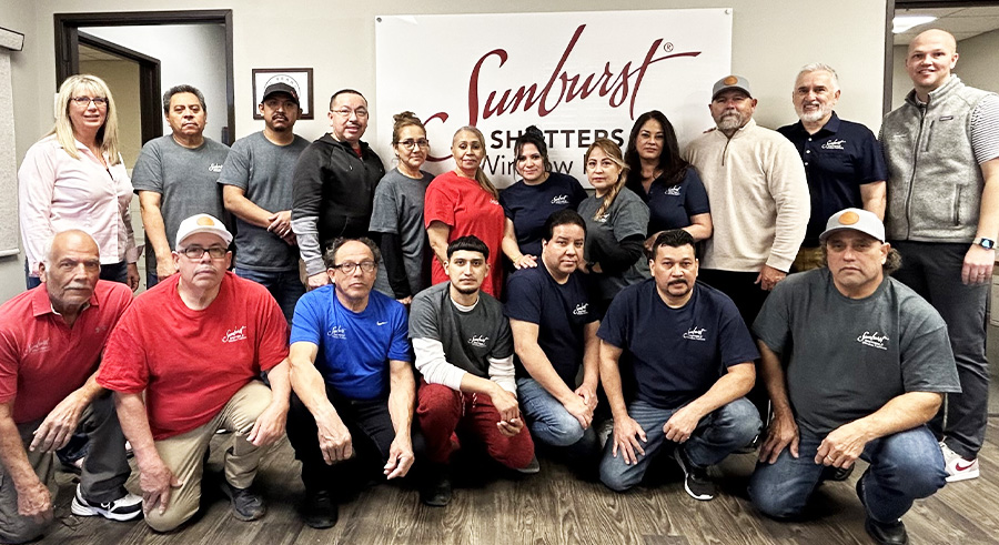 Dallas team sitting or standing in front of the sunburst company banner