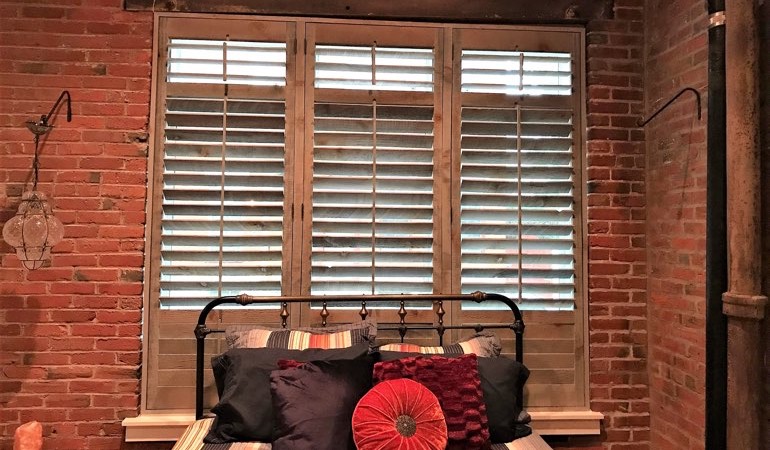 Reclaimed wood shutters give an organic touch to your minimalist design. Reclaimed wood shutters near a brick wall.