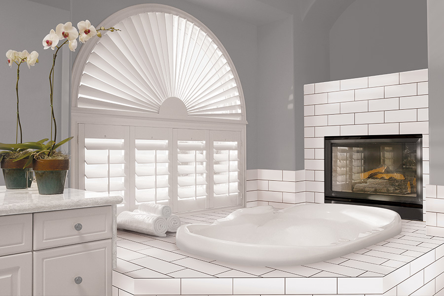 Explore our selection of window treatments for builders in Dallas to find the perfect ones for your next construction project. White Polywood shutters on an arched bathroom window