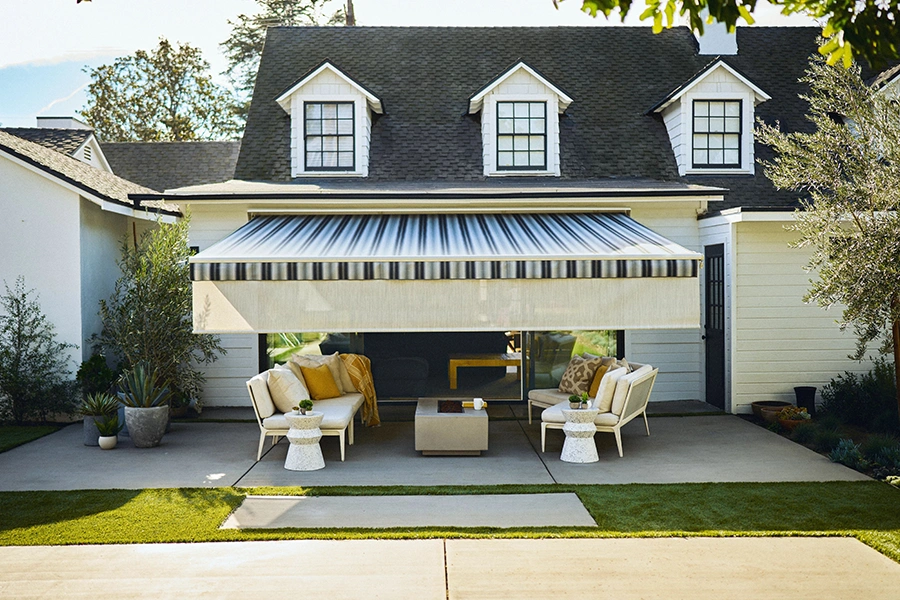 A back patio with furniture and a striped awning over it