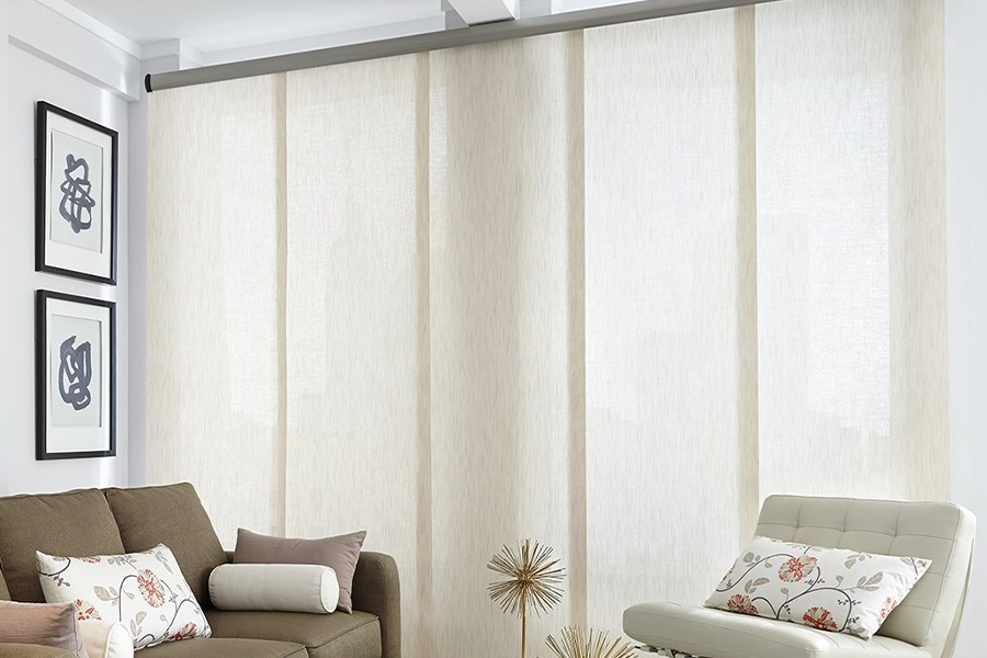 Find window treatments to complete any interior design among our extensive selection at Sunburst Shutters Dallas.  Long off-white window shades on a tall window in a modern living room
