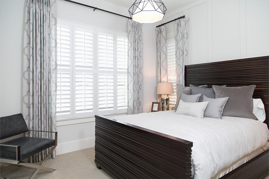 Polywood shutters are durable and pet-friendly. White Polywood shutters in a bedroom.