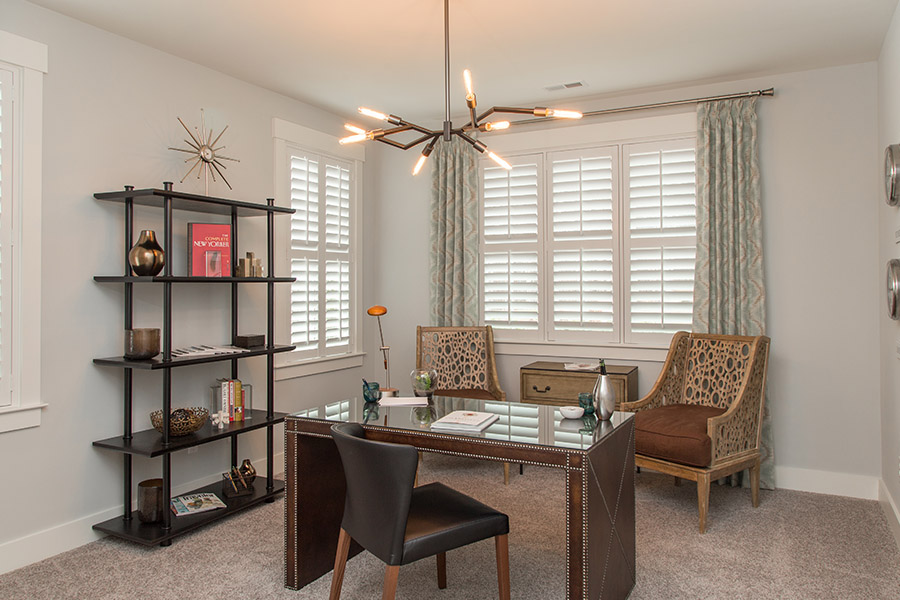Colorful curtains can add a bit of flair with white Polywood shutters in Dallas. Sage green patterned curtains on white polywood shutters in an office.