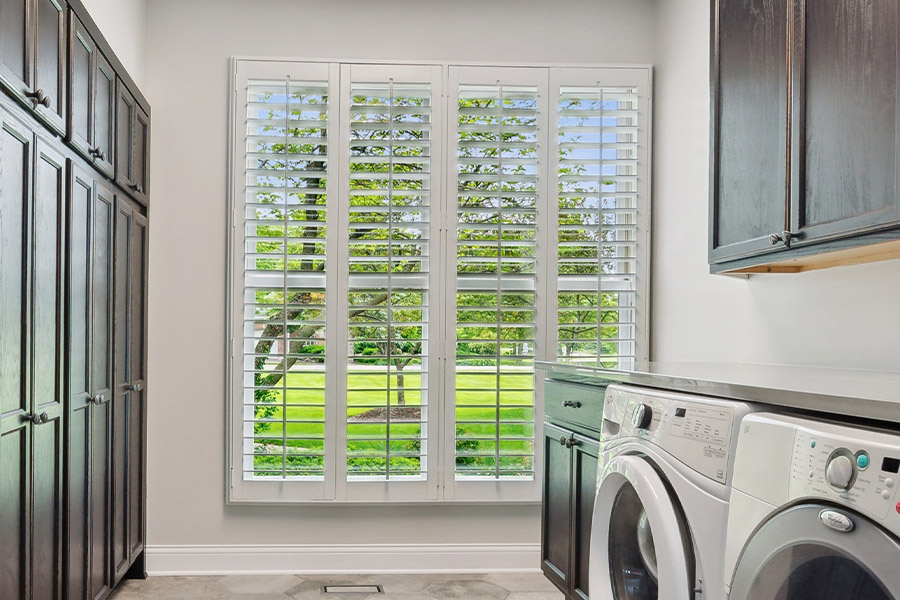 Find the perfect level of natural light for your Dallas laundry room with interior shutters. White Polywood shutters letting light through a laundry room window